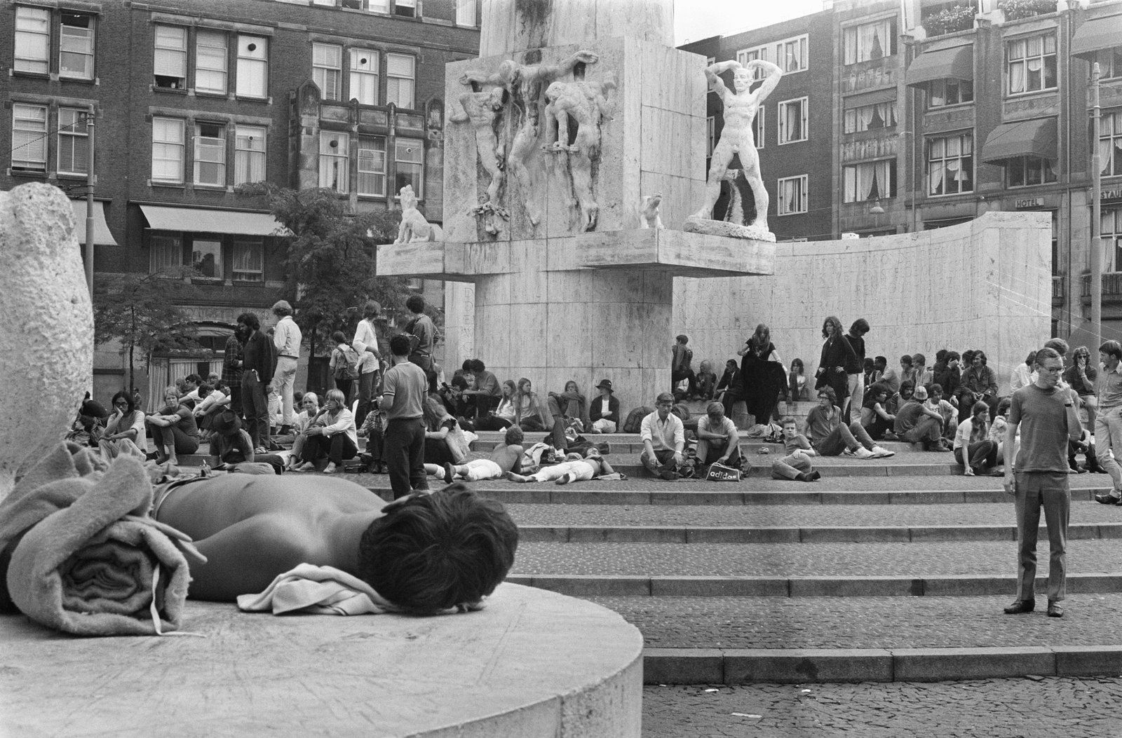 Jongeren zitten en liggen op de trappen van het Nationaal Monument op de Dam