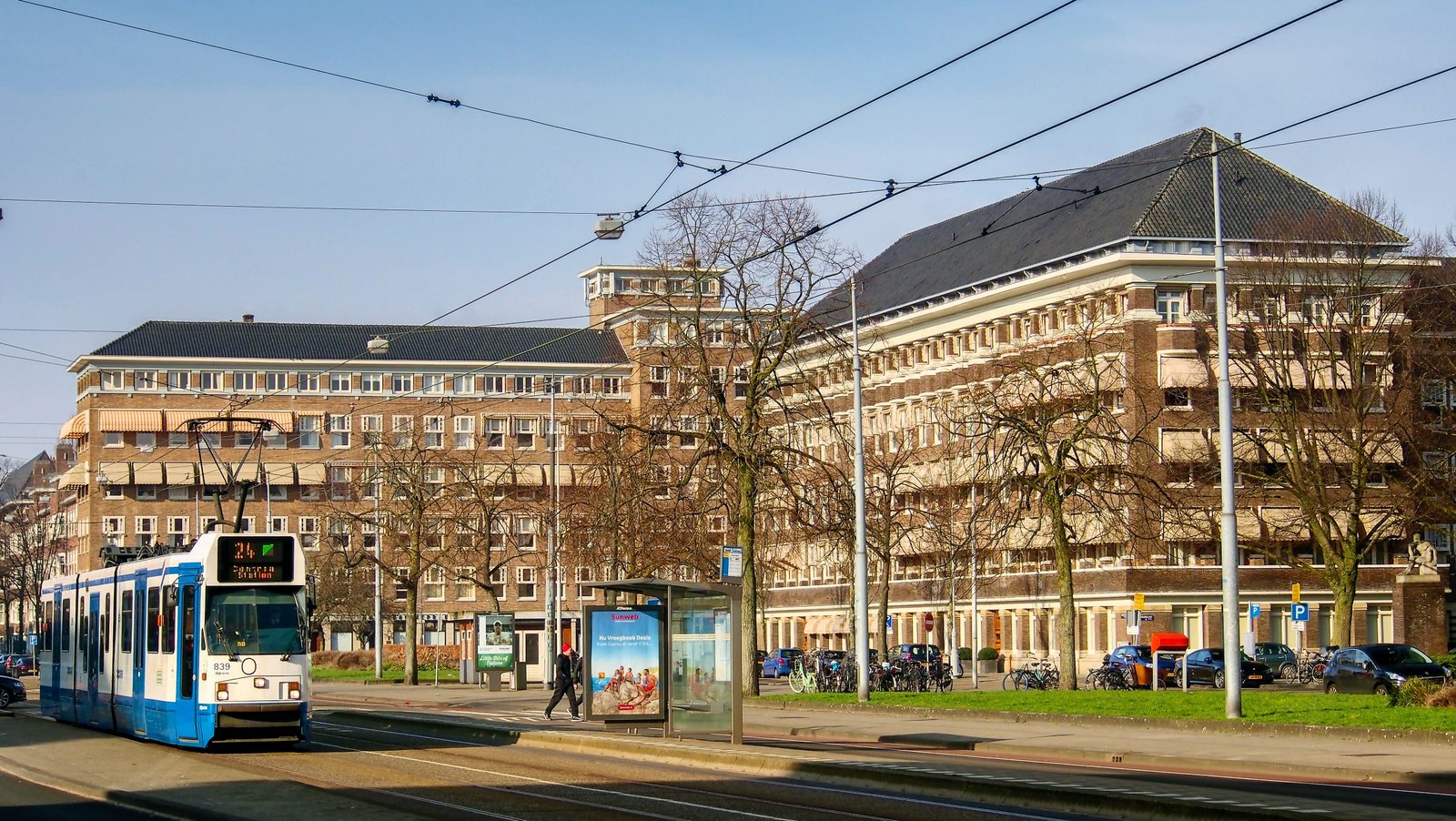 Bakstenen woonblokken met schilddaken rond het Minervaplein, op de voorgrond een tram